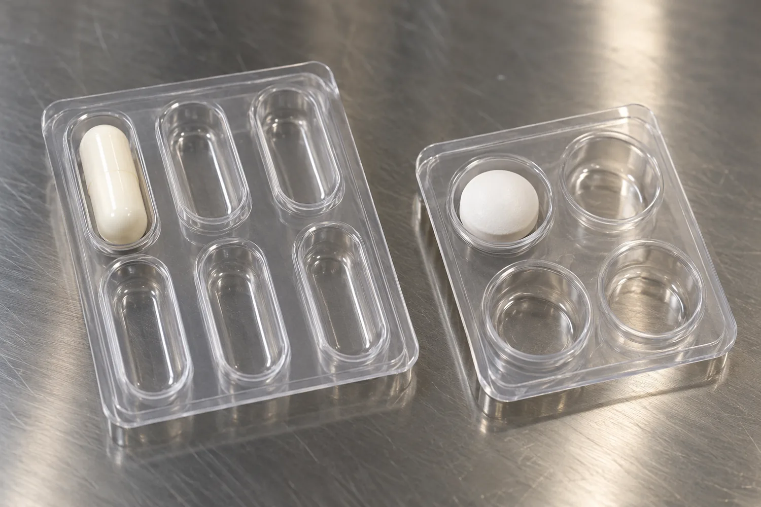 A capsule in an oblong cavity and a tablet in a round cavity, with empty pockets beside them